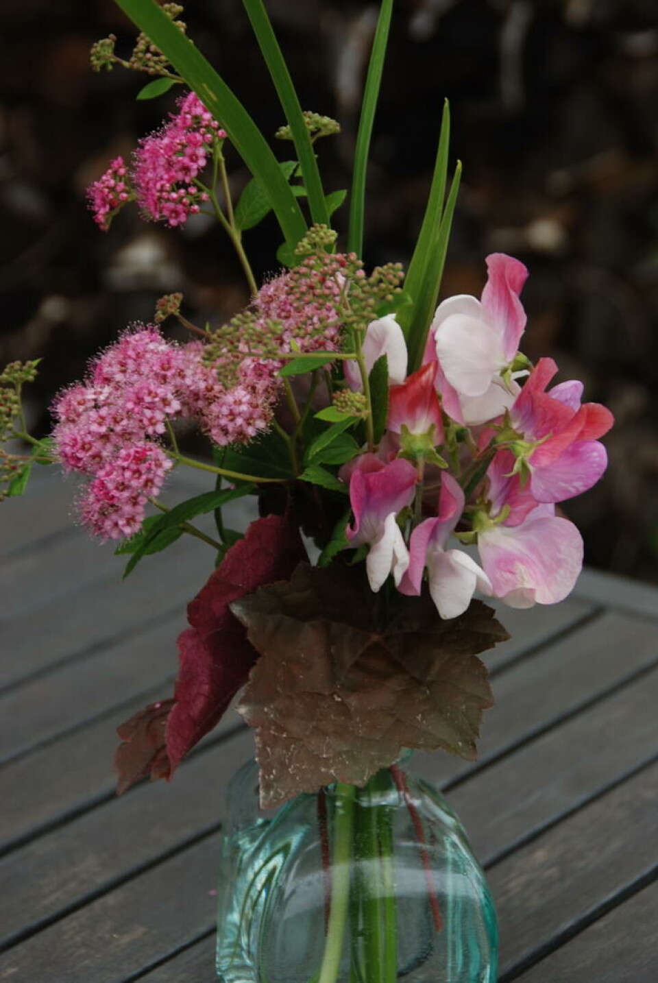Blad fra alunrot og iris, spireablomster og blomsterert. Bukett med stauder