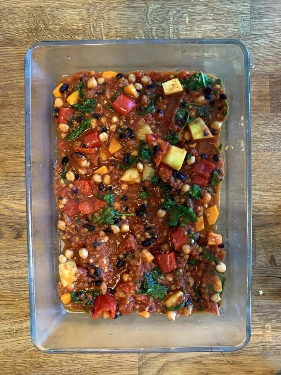 Start med å legge i tomatsausen i bunnen av en smurt form. Tomatsaus med masse grønnsaker i en blank, ildfast form.