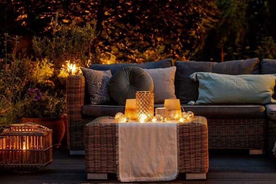 Vann i hagen skaper stemning, lenge før hagen er ferdig. Fotograf: Shutterstock. En uteplass med sofa på kvelden, belyst av elektriske lys og stearinlys.