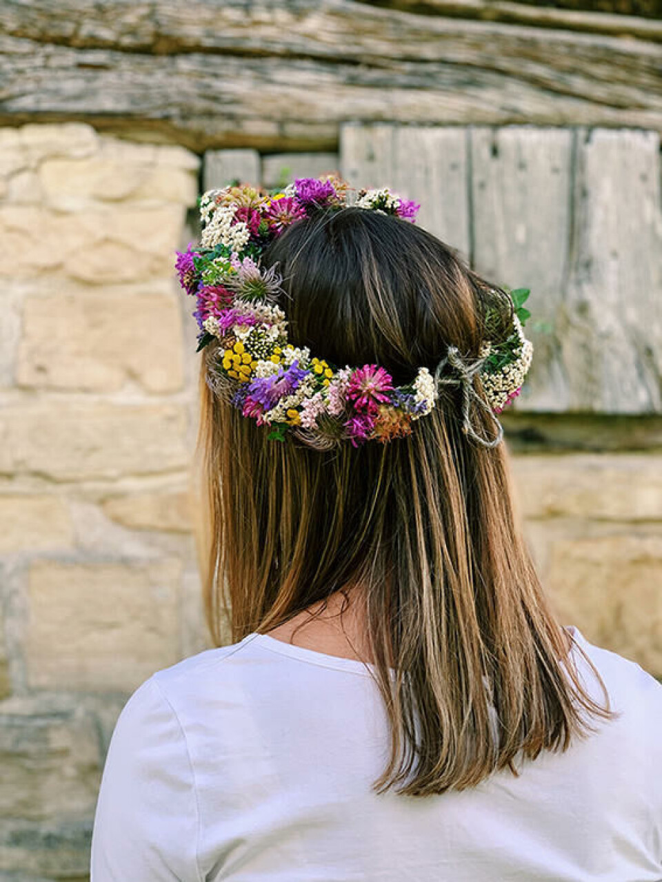 Kransen knyttes bak med et røft julesnøre. Hårkrans av markblomster