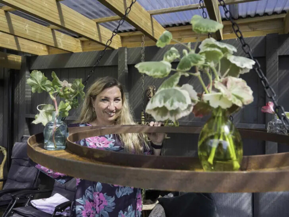 Ann Kristin Selli liker metallsirkelen hun har hengt opp i hagestua på hytta. Den kan dekoreres etter sesong. Nå er det pelargoniastiklinger som har fått plass.. Fotograf: Kari Kløvstad. metallsirkel