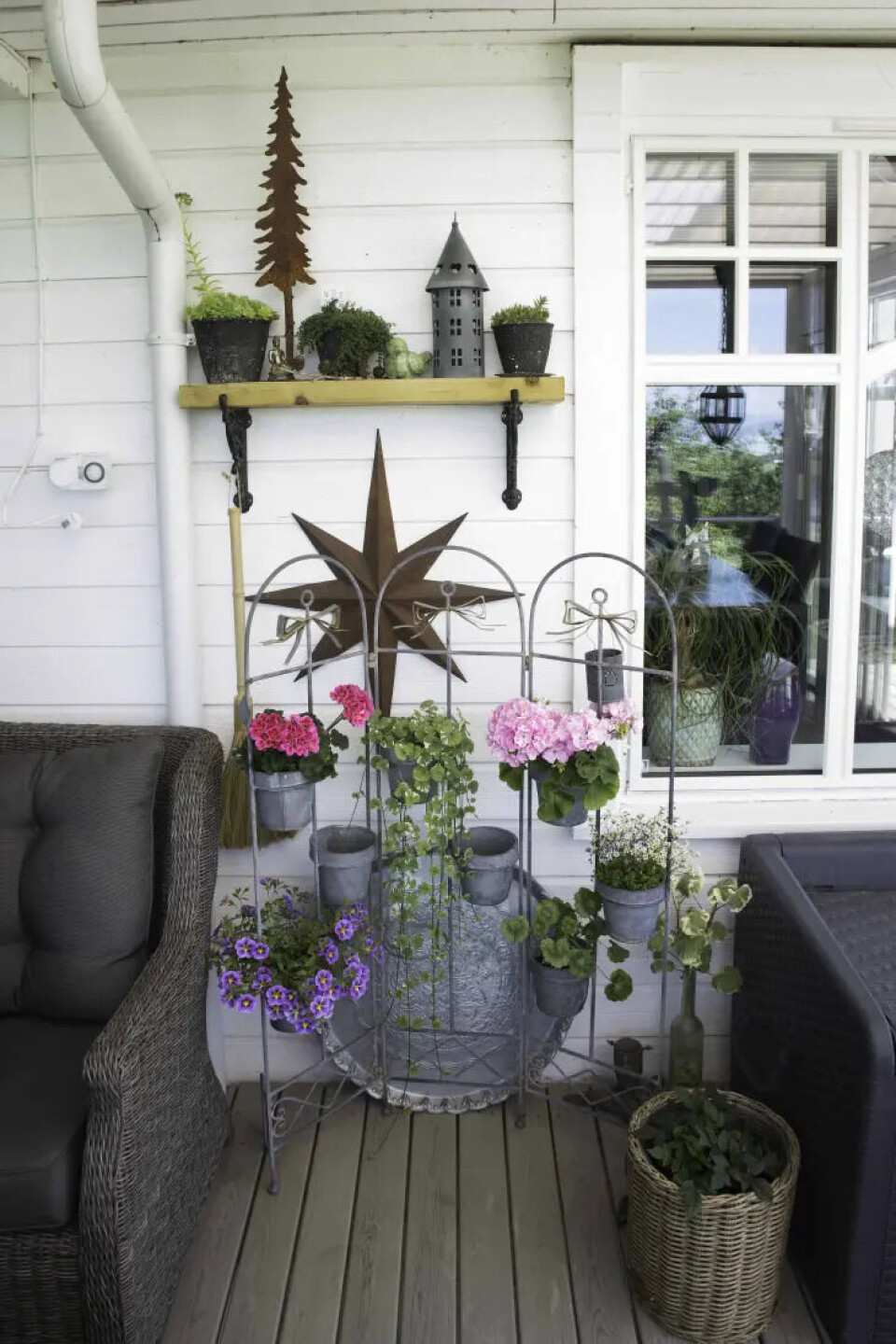 På verandaen har Ann Kristin brukt kreativiteten sin. I midten står et stativ med sju potter, der plantene kan byttes ut gjennom sesongen.. Fotograf: Kari Kløvstad. veranda