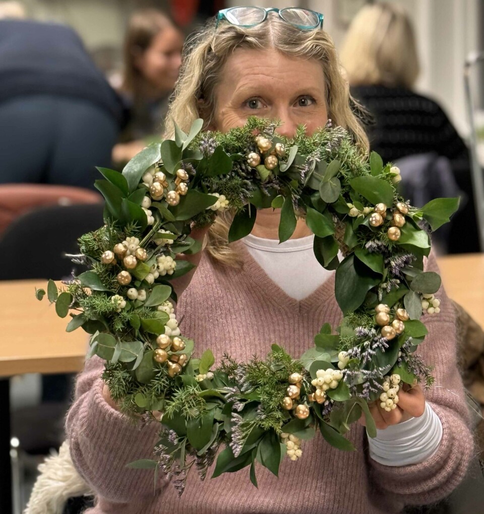 Åshild Håbu Kristoffersen holder opp kransen hun har laget på Hvaler hagelags kranseverksted.